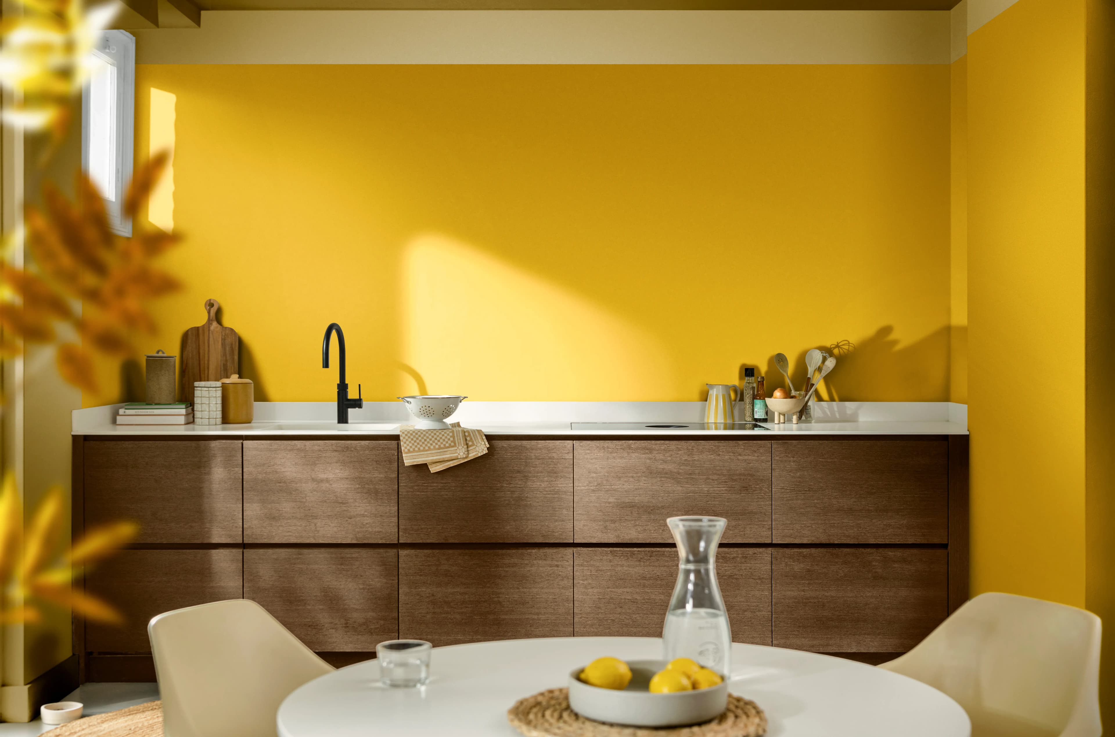 Modern kitchen with yellow walls and wooden cabinets, styled with minimalist décor and bathed in natural light.