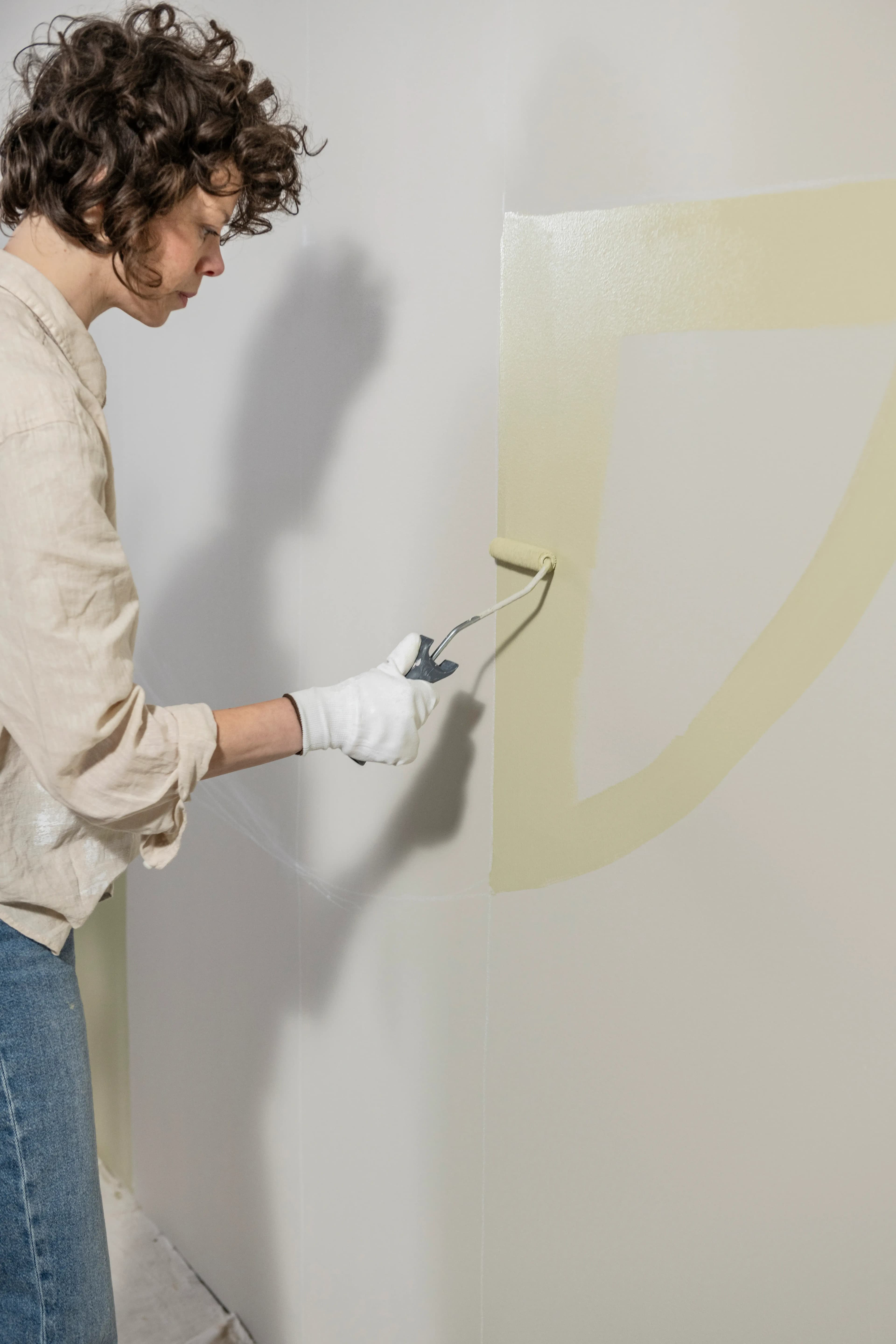 Someone using a roller to paint a coloured shape.