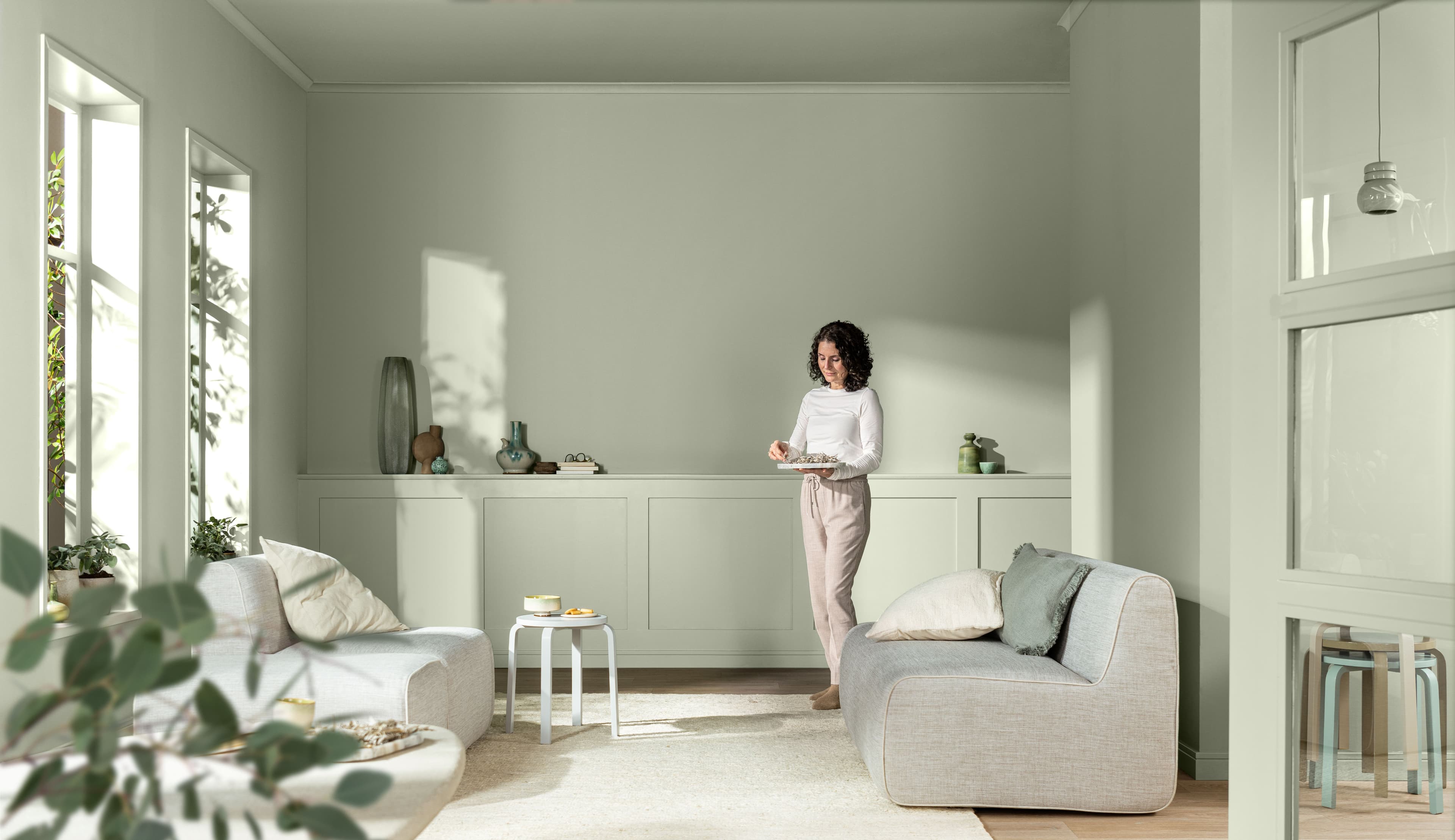 Living room painted entirely in sage green with person