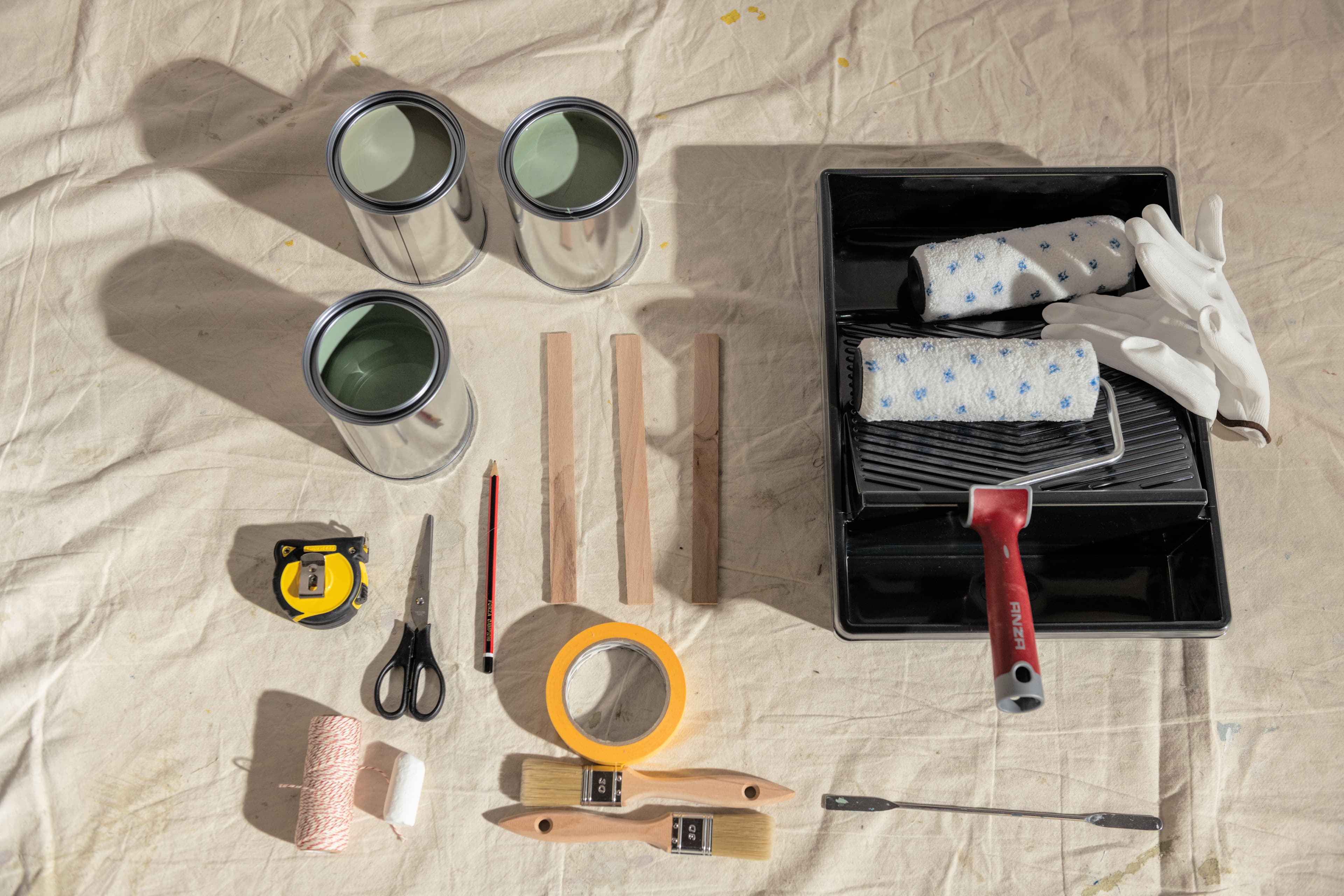 Paint and painting accessories displayed on a dust sheet