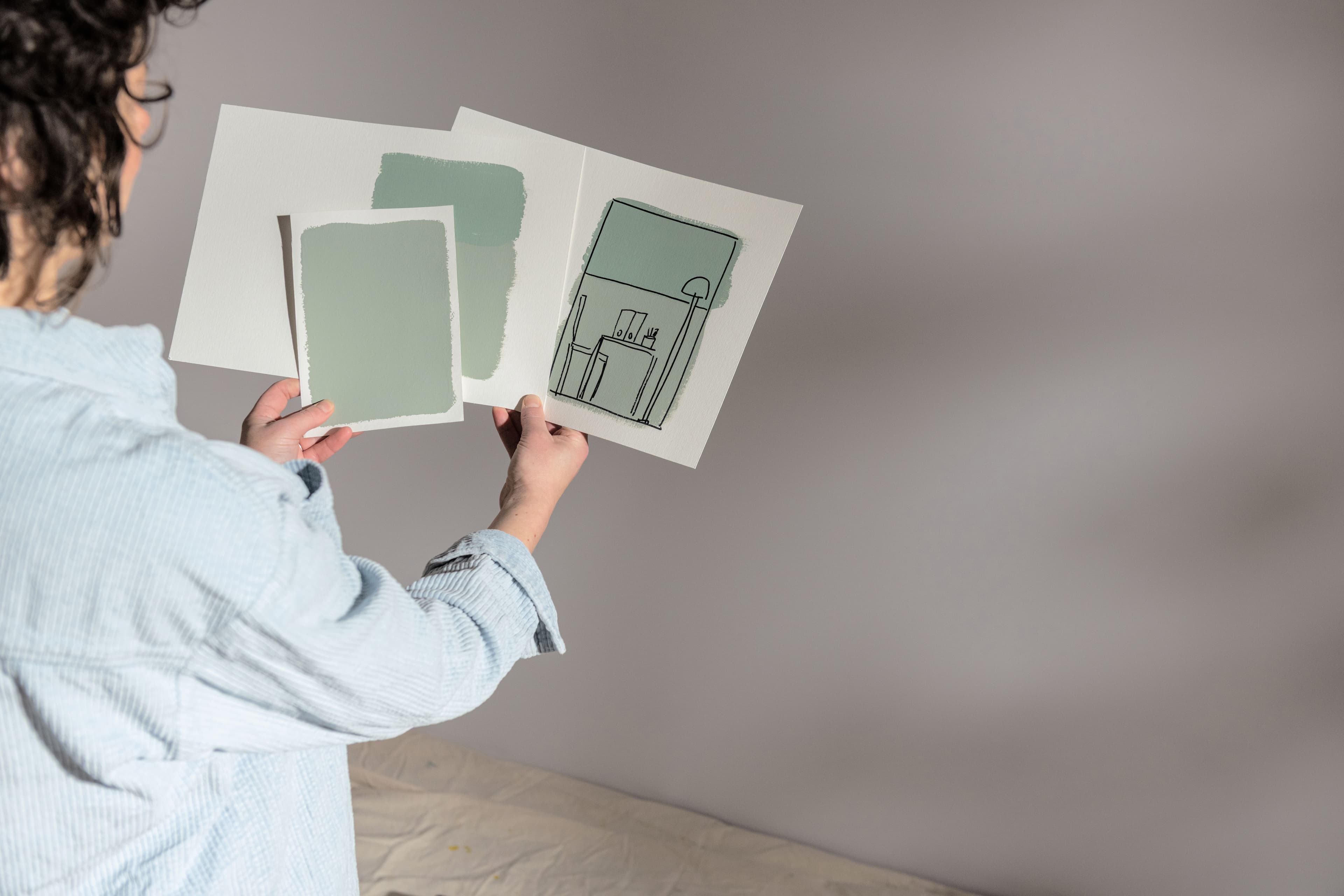Someone looking at sketch colour plan and paint swatches