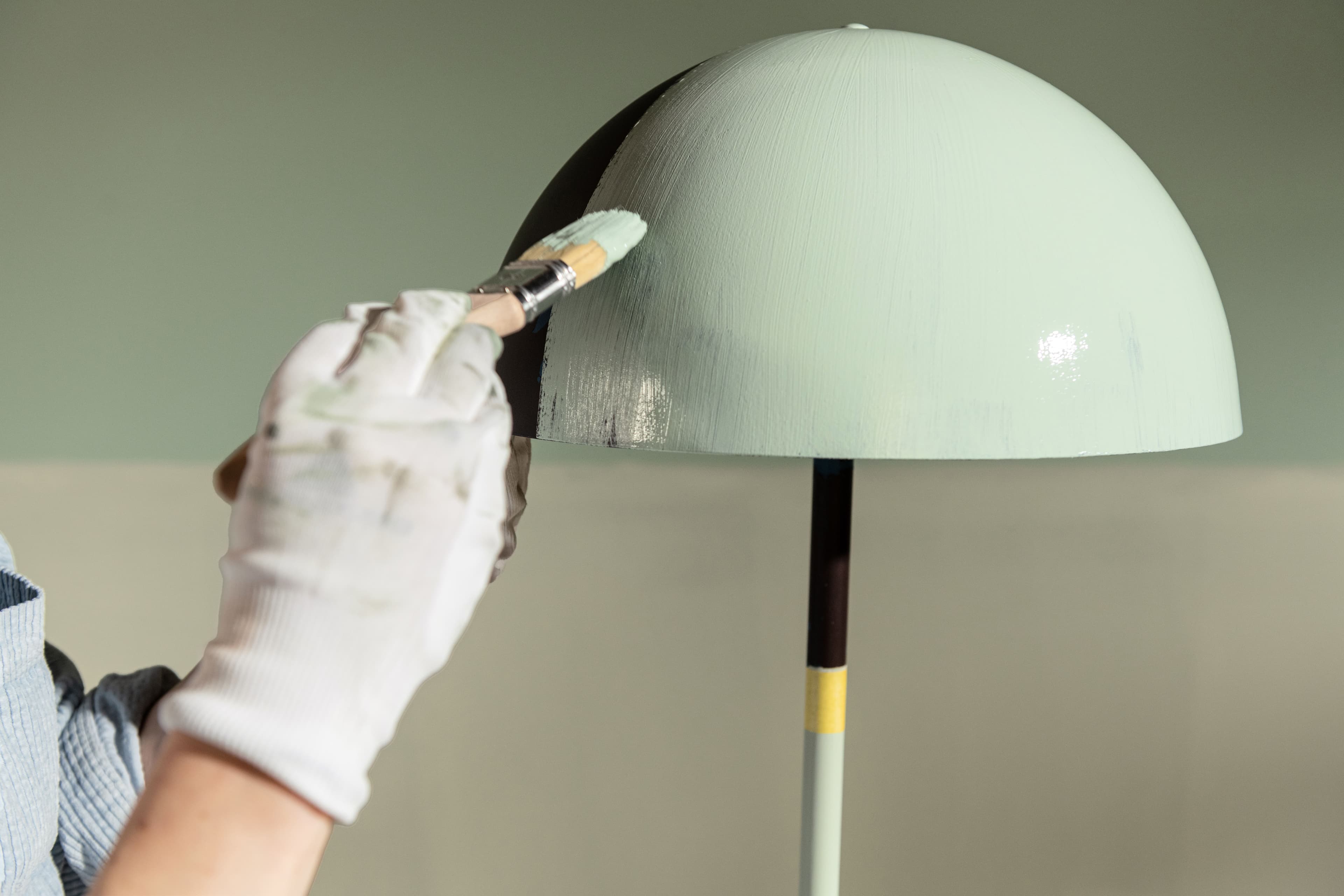 Someone painting the top of a lamp in green